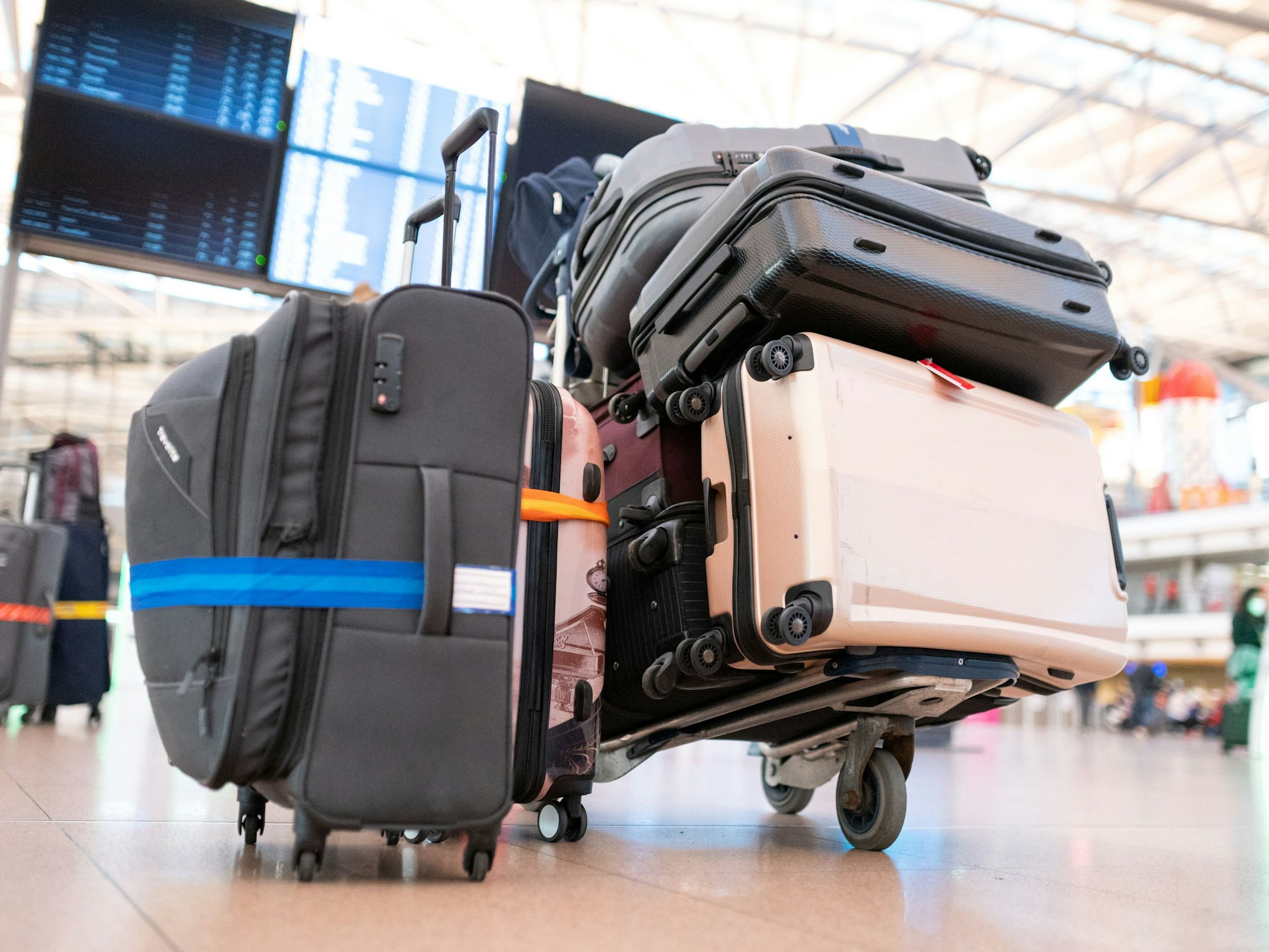 Mehrere Koffer liegen auf einem Gepäckwagen in einer Schlange vor einem Check-in-Schalter, hier im Oktober 2021 in Hamburg.