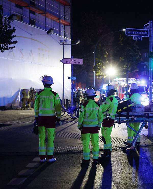 Mehrere Einsatzkräfte der Feuerwehr stehen vor einem Gebäude, an der Straße parkt ein Löschfahrzeug.