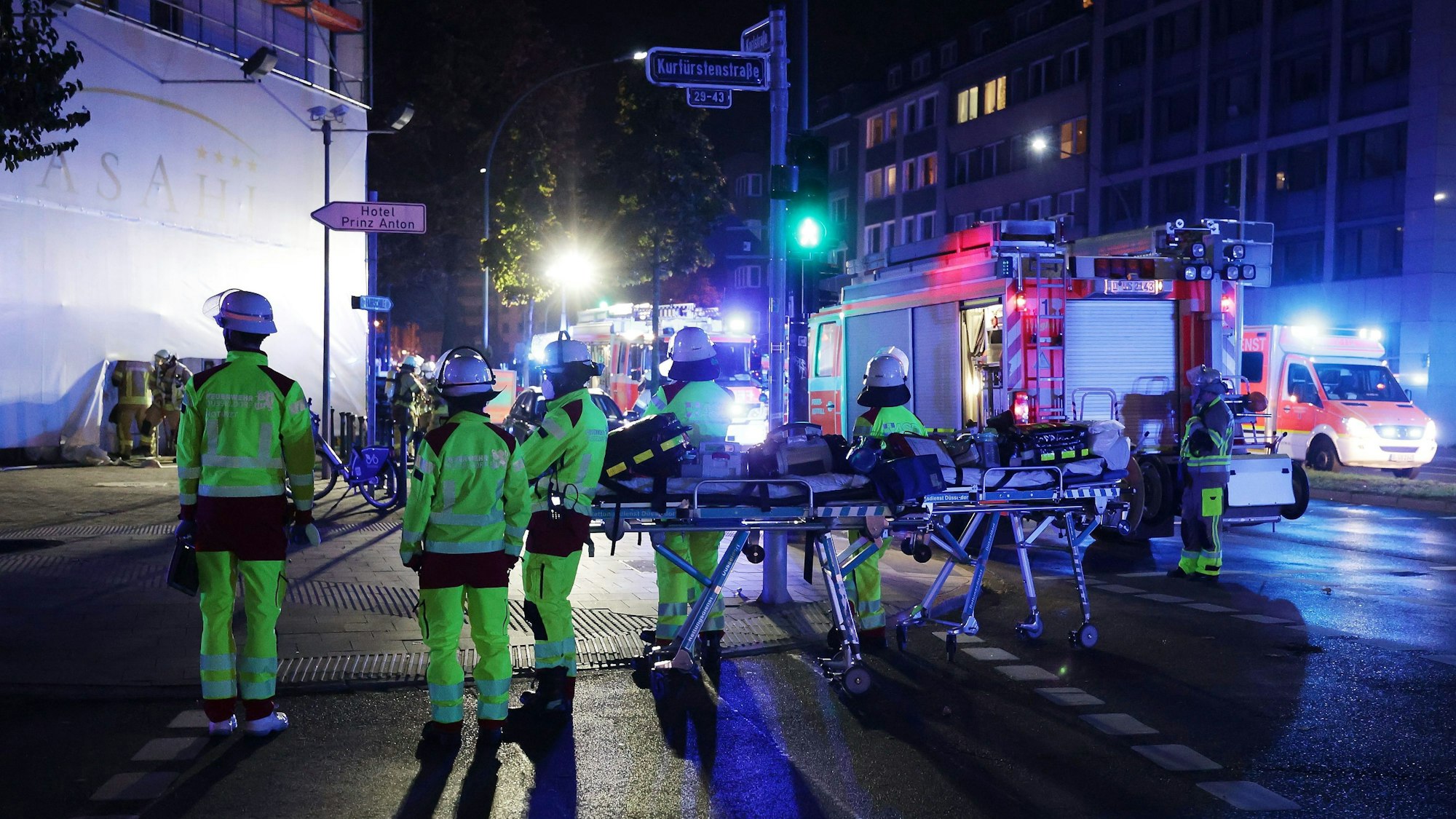 Mehrere Einsatzkräfte der Feuerwehr stehen vor einem Gebäude, an der Straße parkt ein Löschfahrzeug.