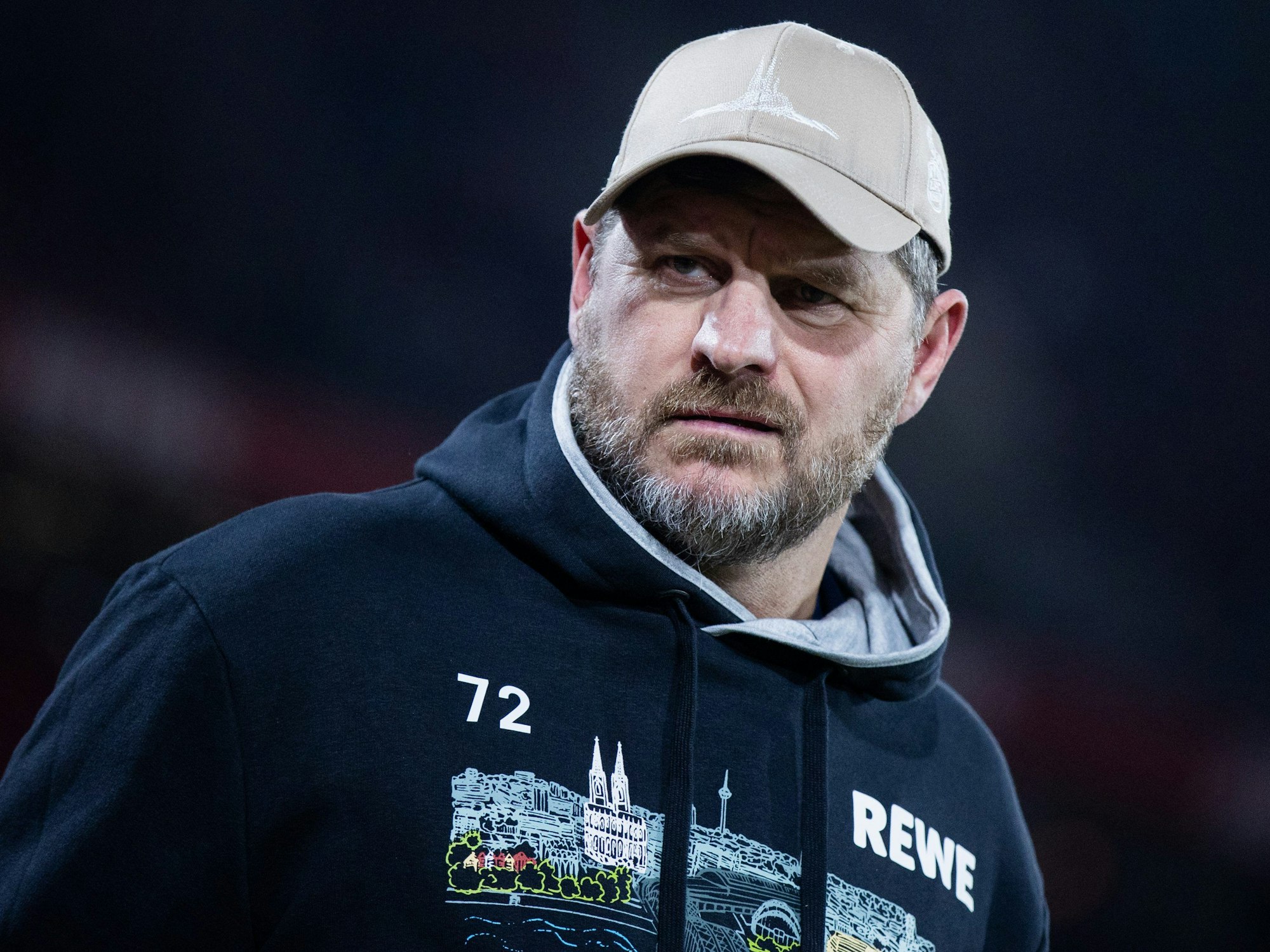 Steffen Baumgart in dunklem Pullover und Kappe, er schaut grimmig.