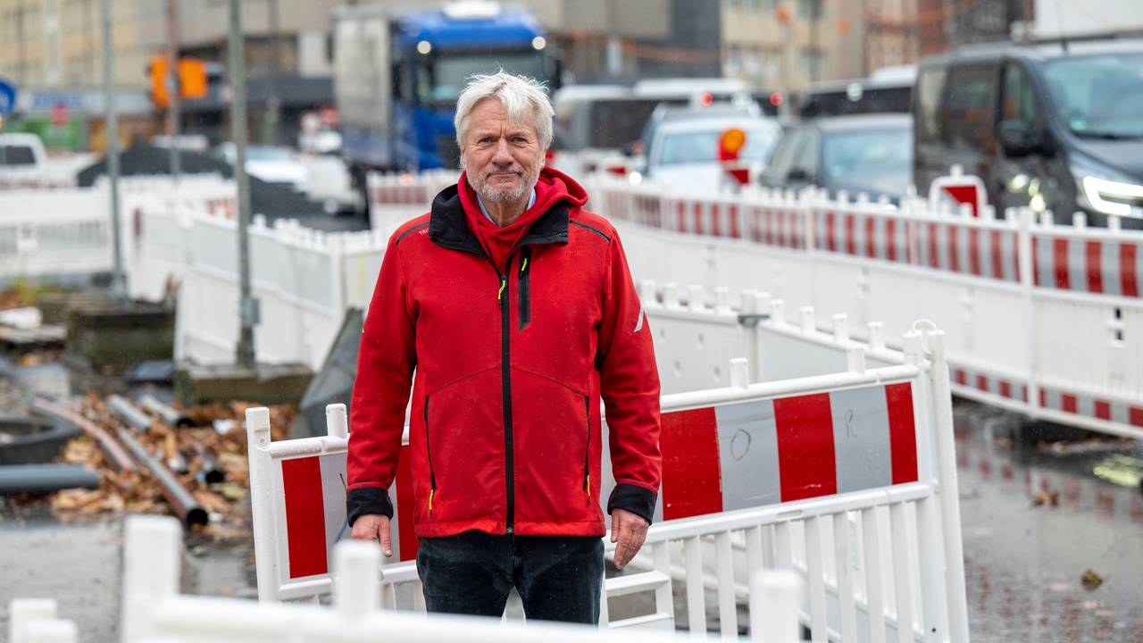 Jürgen Becker steht zwischen Baustellenbaken auf einer Baustelle in Köln.