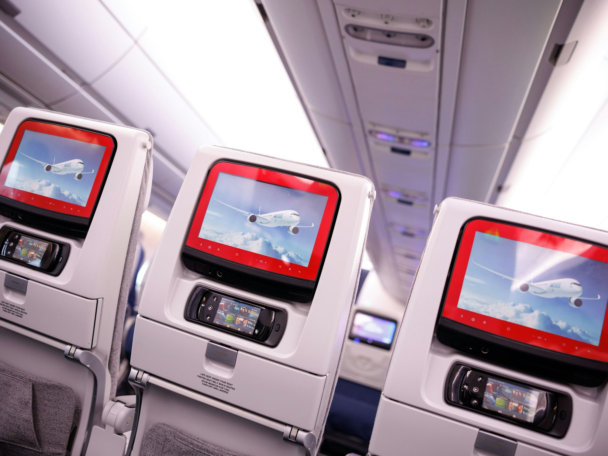 Monitore sind bei einem Medientermin zur Besichtigung des Airspace Explorer-Testflugzeugs von Airbus in den Kopfstützen der Sitze der Economy Class zu sehen, hier im Dezember 2022 in München (Symbolfoto)