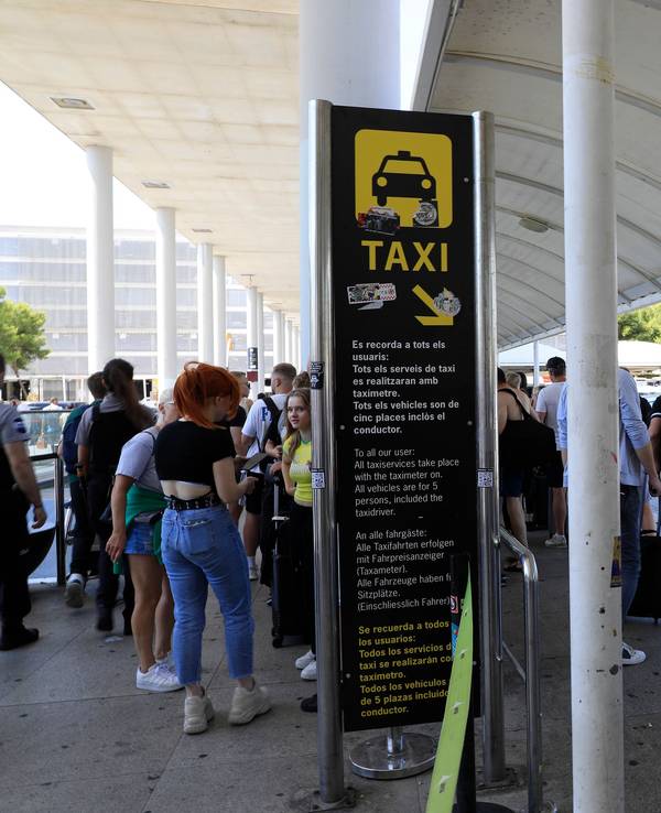 Reisende stehen am Flughafen von Mallorca in einer Schlange und warten auf Taxis.