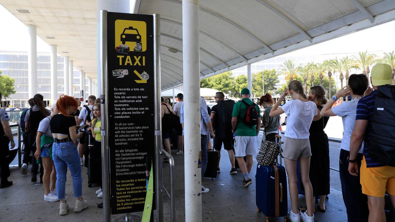 Reisende stehen am Flughafen von Mallorca in einer Schlange und warten auf Taxis.