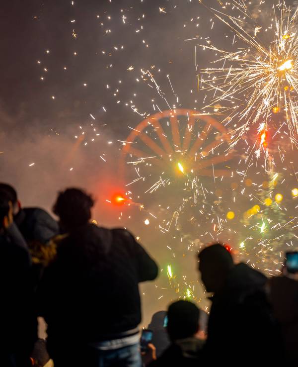 Menschen schauen in den Nachthimmel, an dem Feuerwerksraketen explodieren.