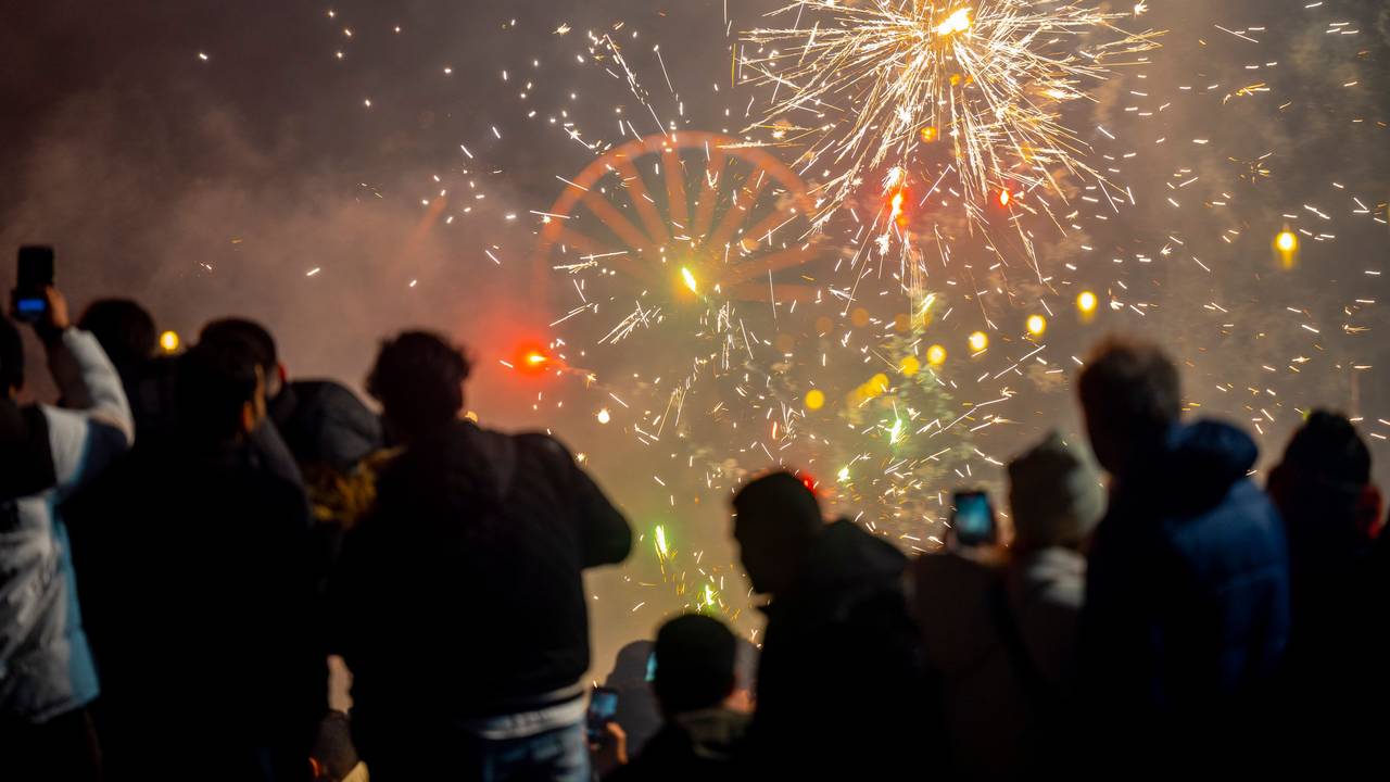 Menschen schauen in den Nachthimmel, an dem Feuerwerksraketen explodieren.