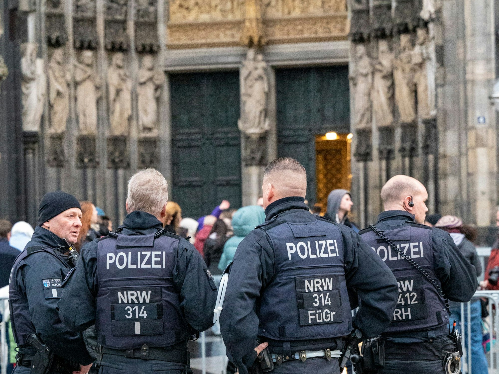 Vier Polizisten stehen an einem Absperrgitter am Kölner Dom.
