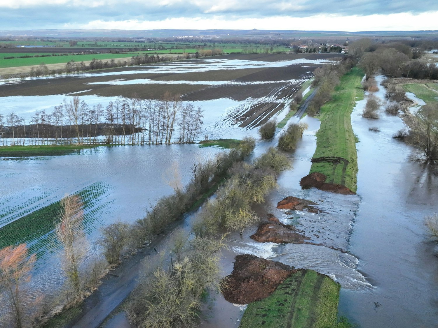 Mönchpfiffel-Nikolausrieth am 29. Dezember 2023: Wassermassen fließen durch die Deichöffnung am Fluss Helme auf die umliegenden Flächen. Um die Hochwassergefahr an der Landesgrenze zwischen Thüringen und Sachsen-Anhalt zu entspannen, ist der Deich kontrolliert geöffnet worden.