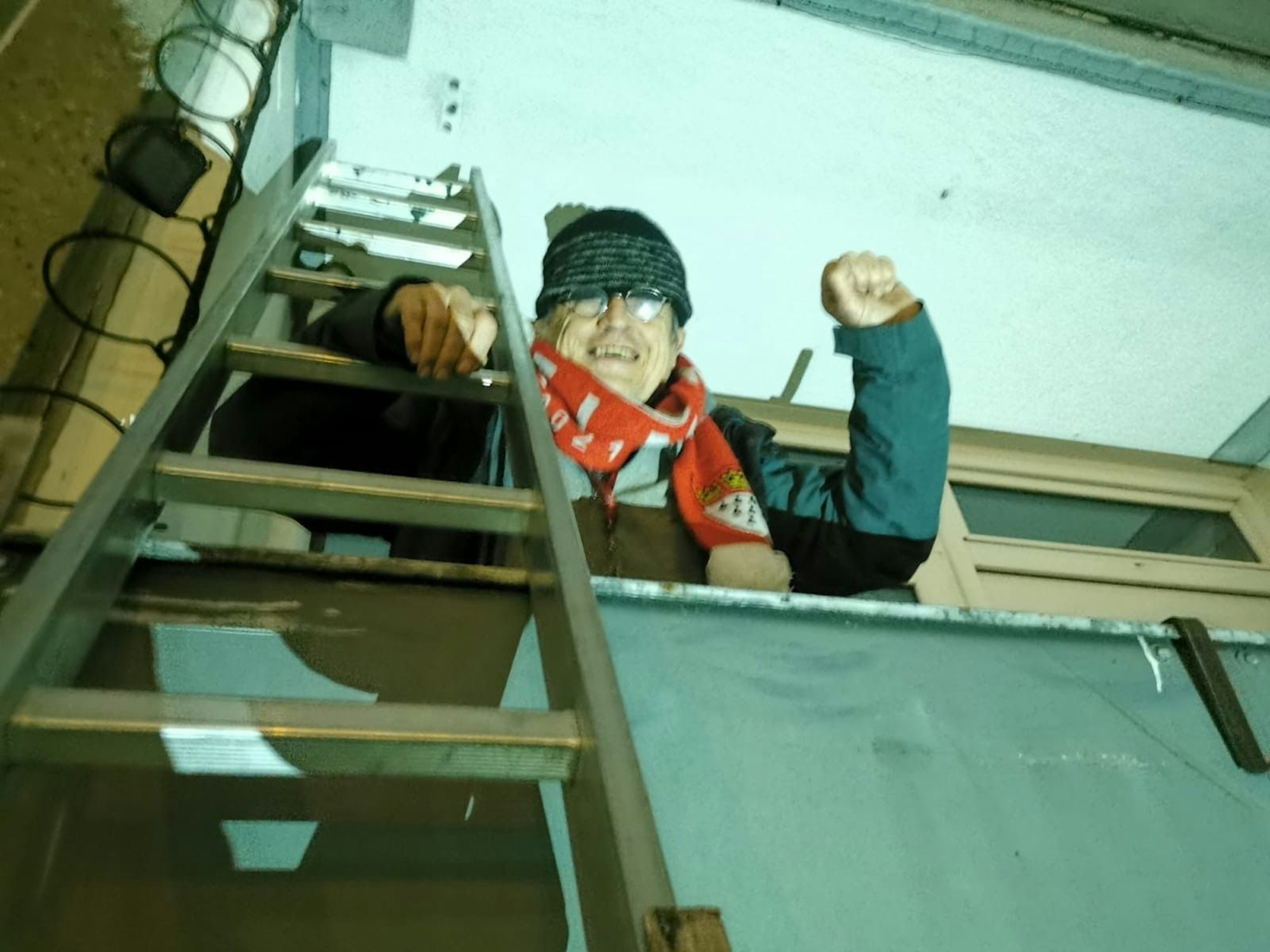 Rainer Kippe steht auf einem Balkon, an dem eine Leiter lehnt, und freut sich.