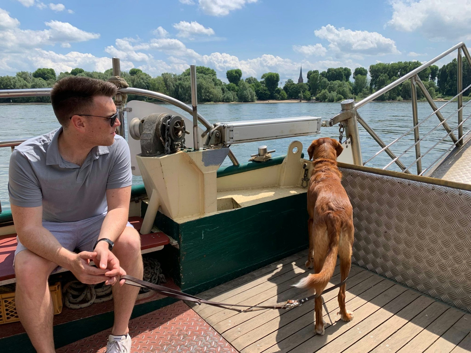 Pascal Eichler sitzt auf der Fähre und hält Hündin Paula an der Leine, die über die Reling guckt.