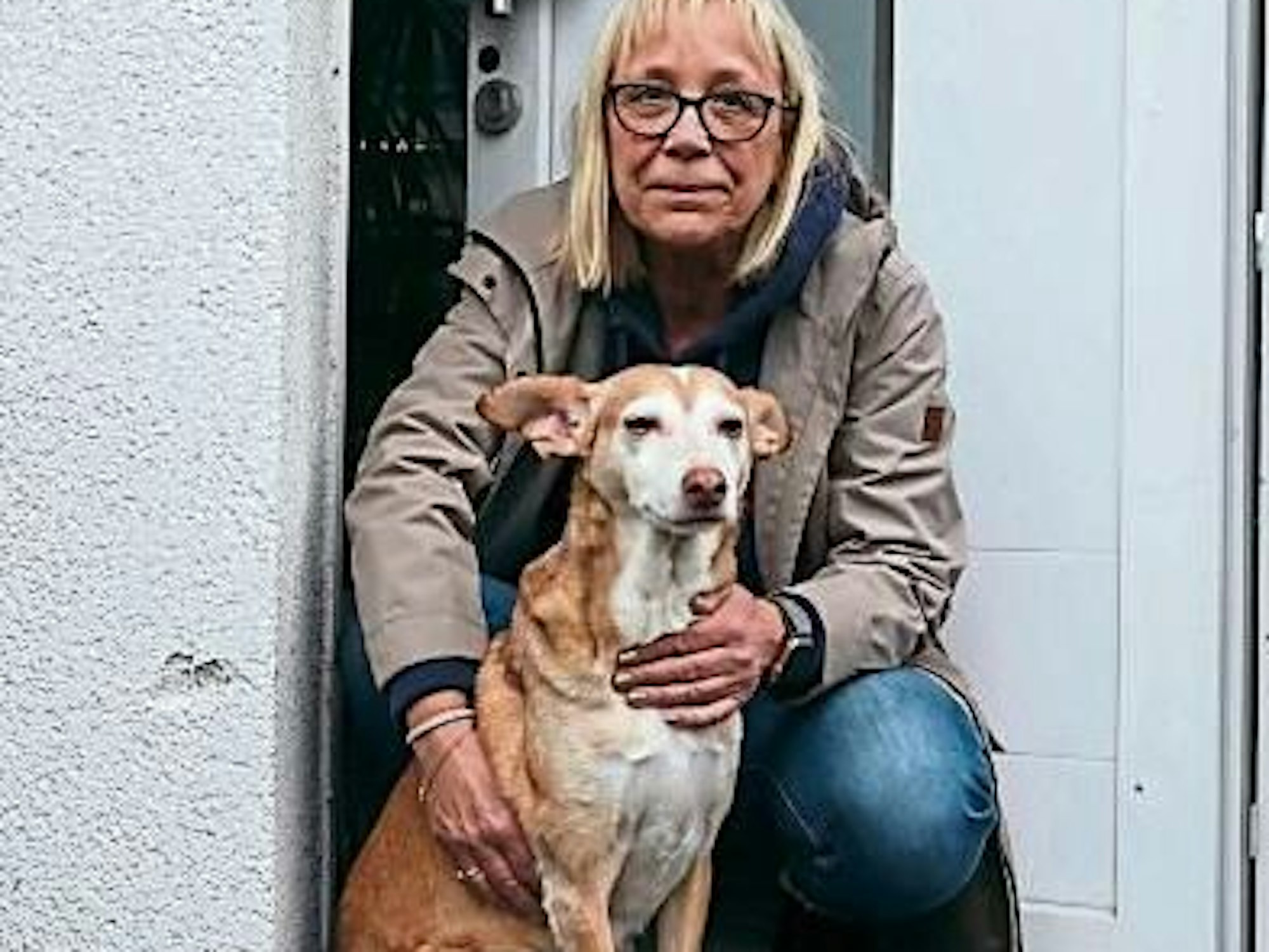 Simone Bley hockt vor ihrer Haustür, neben sich Hündin Alma.