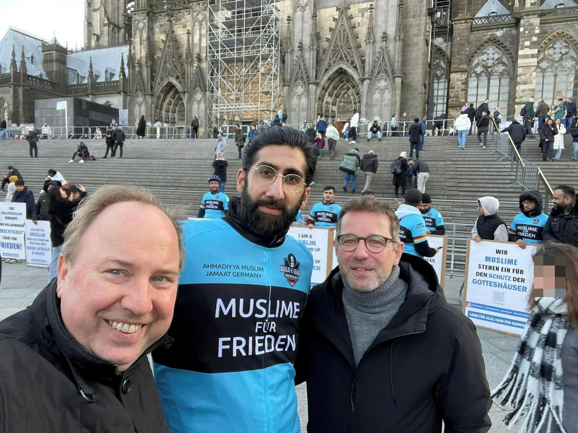 Drei Männer stehen vor der Treppe zum Kölner Dom.