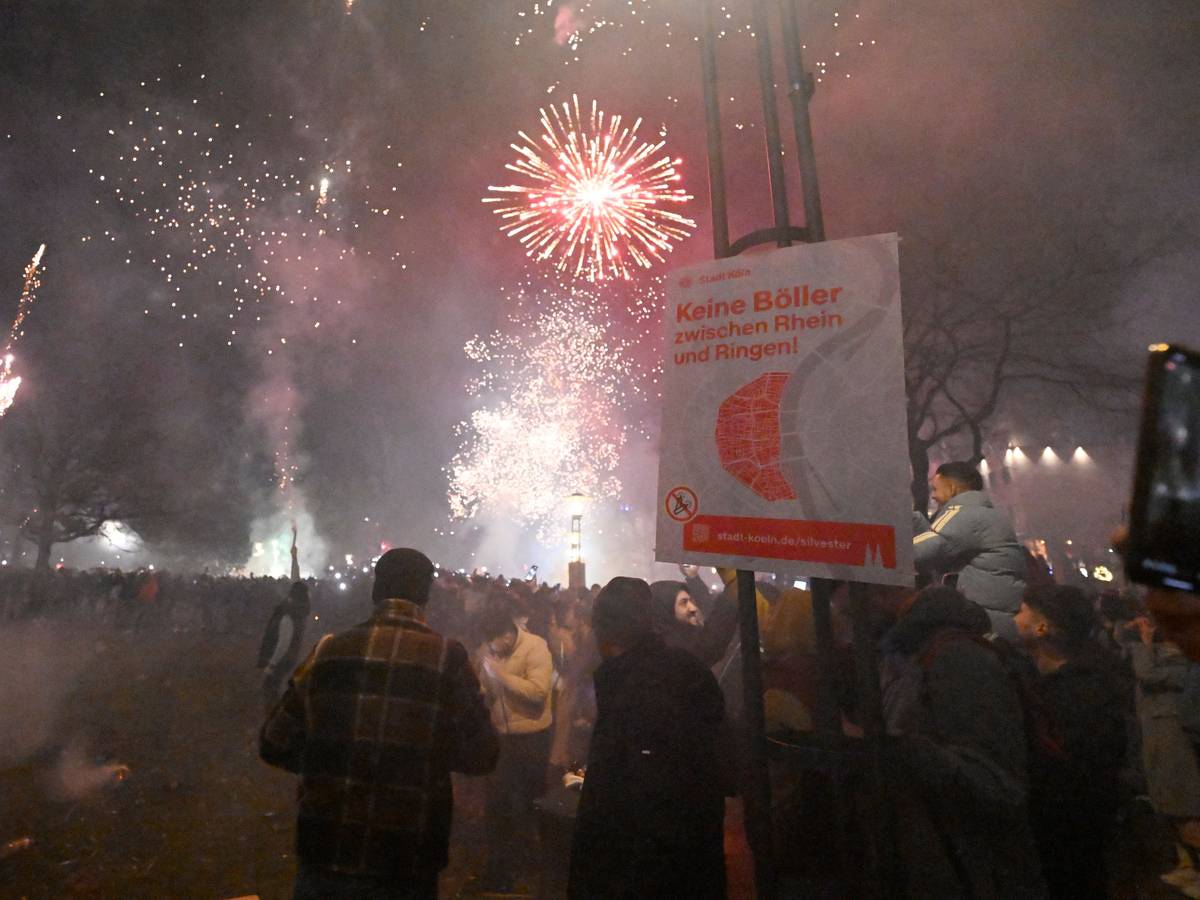 Menschen zünden in der Altstadt Feuerwerkskörper vor dem Böllerverbotsplakat.