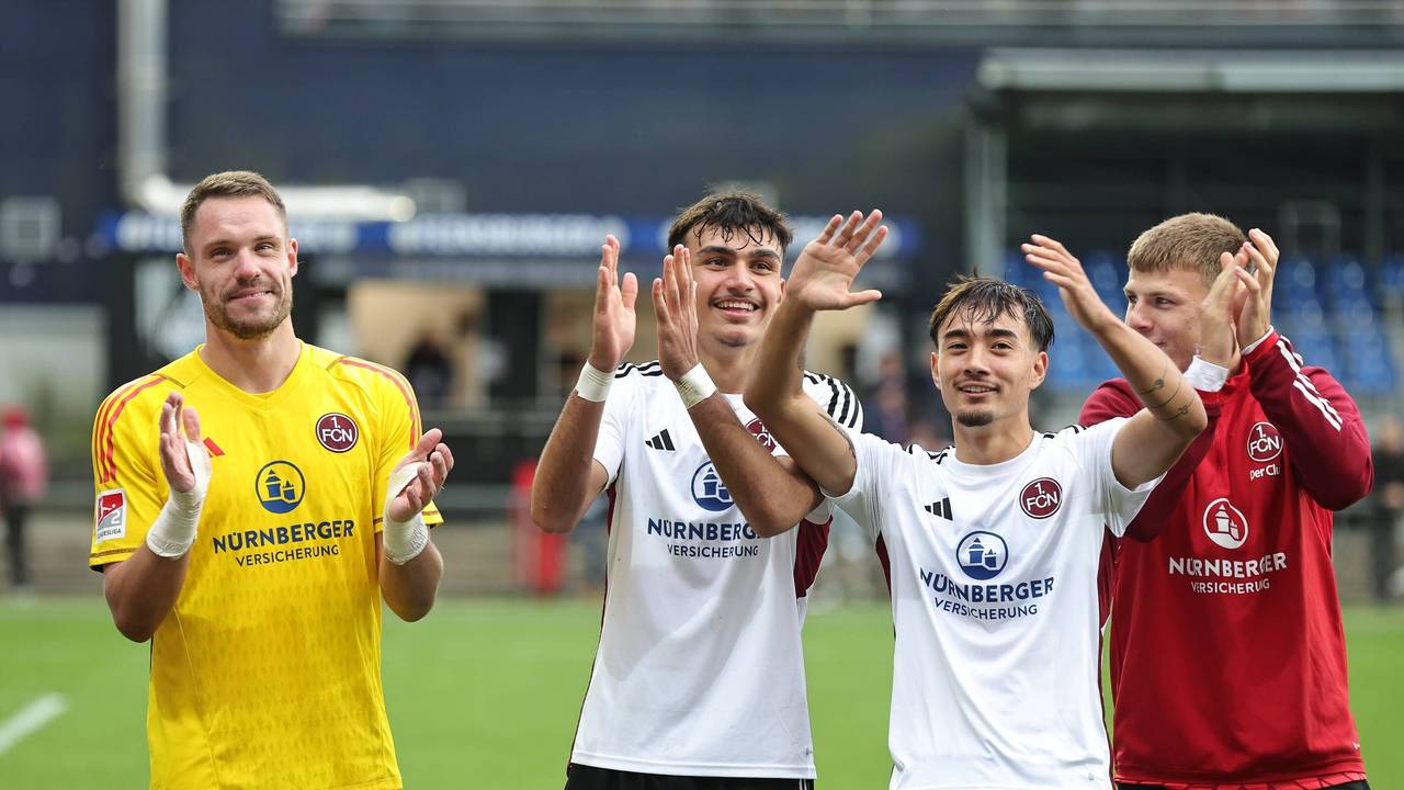 Die Nürnberg-Profis Christian Mathenia, Can Uzun, Jens Castrop und Finn Jeltsch feiern gemeinsam vor dem Fanblock.