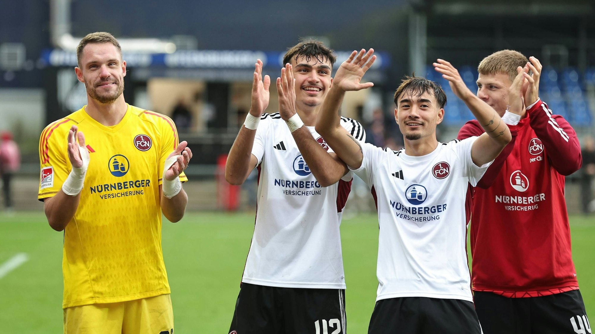 Die Nürnberg-Profis Christian Mathenia, Can Uzun, Jens Castrop und Finn Jeltsch feiern gemeinsam vor dem Fanblock.