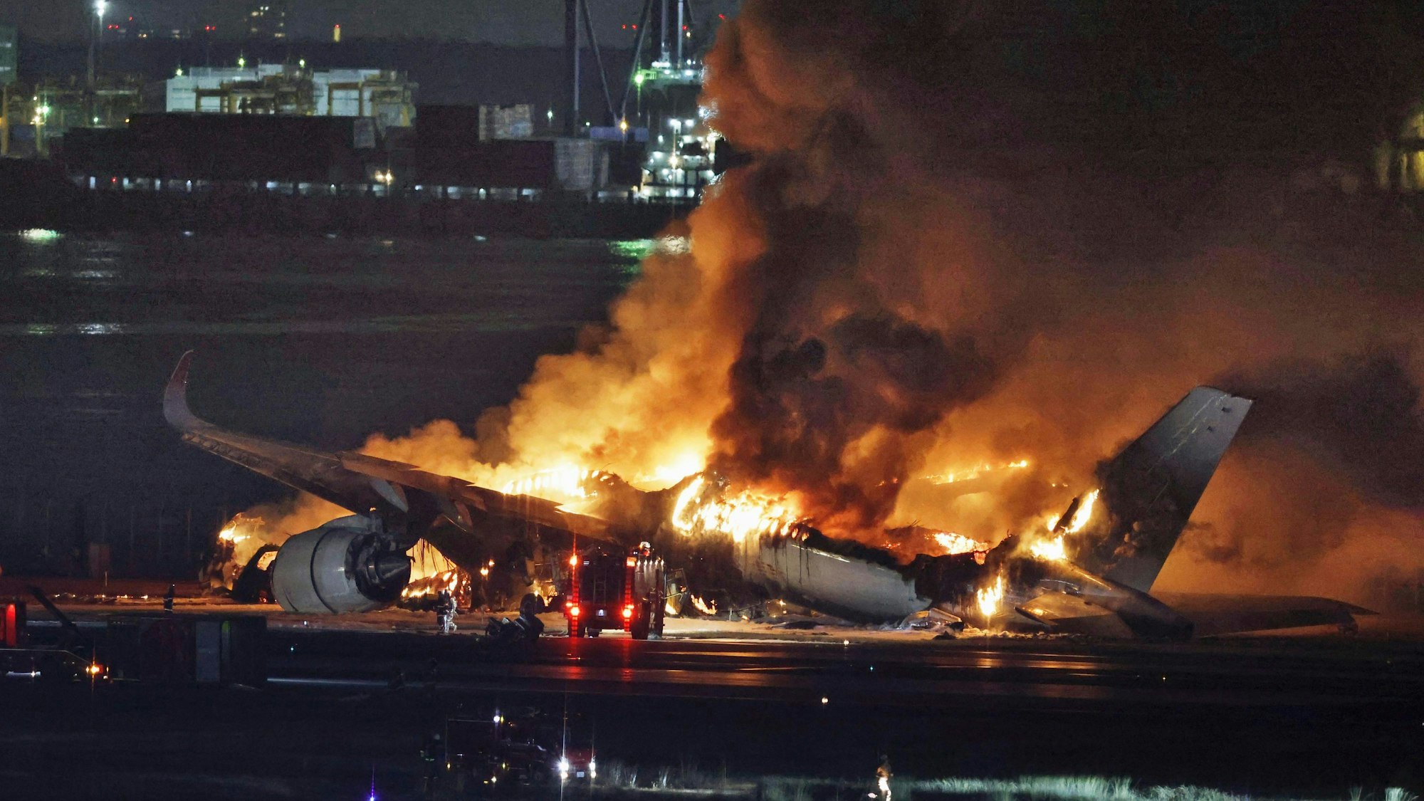 Ein Flugzeug der Japan Airlines brennt auf der Landebahn des Tokioter Flughafens Haneda. Auf Live-Bildern des japanischen Fernsehsenders TBS war am Dienstagabend (Ortszeit) zu sehen, wie Passagiere während der Löscharbeiten die Maschine über eine Notrutsche verließen.