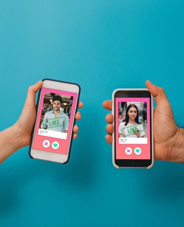 Conceptual image of two hands holding smart phones with an online dating app on the screen. Online dating app concept. Blue background.