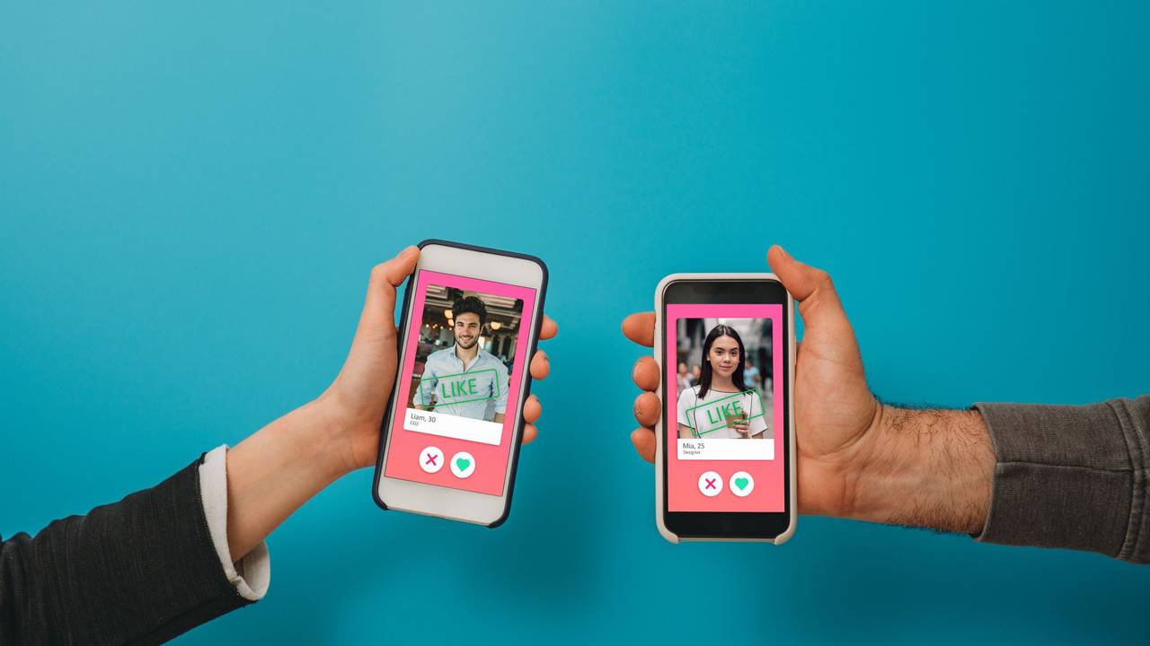 Conceptual image of two hands holding smart phones with an online dating app on the screen. Online dating app concept. Blue background.