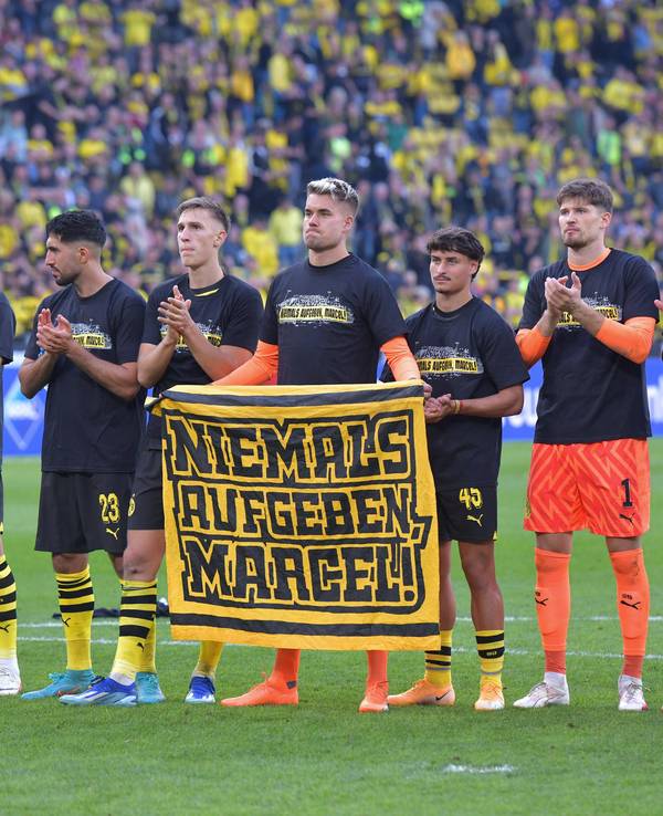 Die Profis von Borussia Dortmund halten ein Plakat mit der Aufschrift „Niemals aufgeben, Marcel“ hoch.