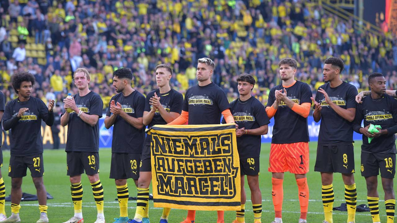 Die Profis von Borussia Dortmund halten ein Plakat mit der Aufschrift „Niemals aufgeben, Marcel“ hoch.