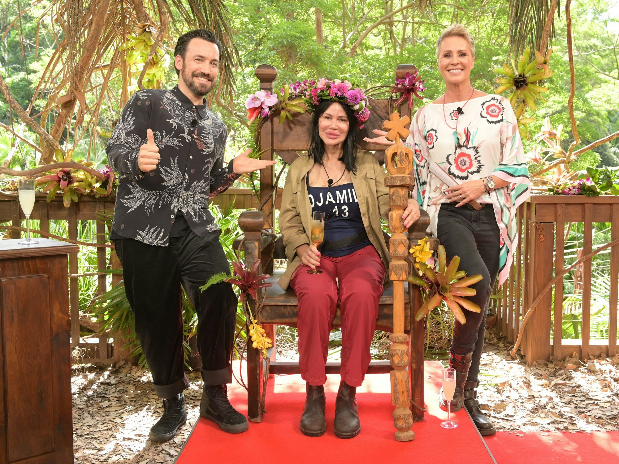 Djamila Rowe sitzt mit ihrer Krone nach dem Sieg beim RTL-Dschungelcamp 2023 auf ihrem Thron neben der Moderatorin Sonja Zietlow und Moderator Jan Köppen.