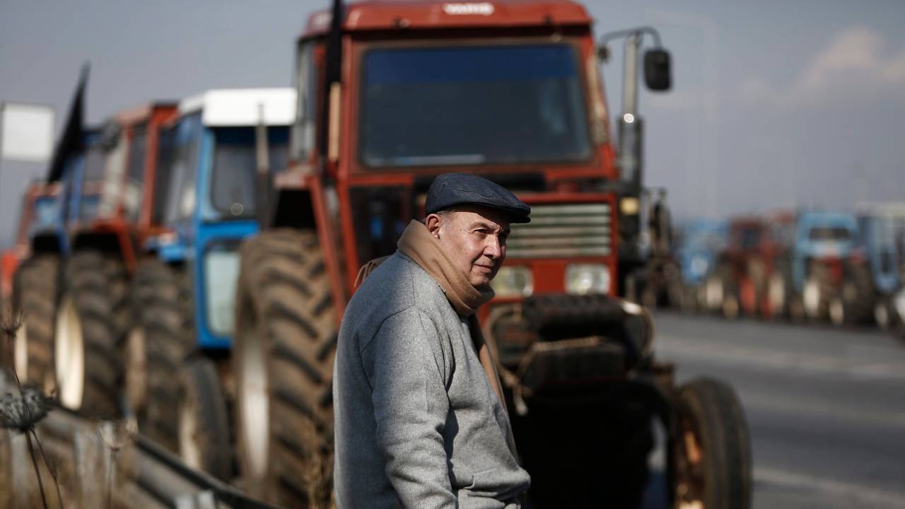 Das Foto vom 26. Januar 2016 zeigt einen Landwirt, der neben geparkten Traktoren am Rand einer Straße sitzt.
