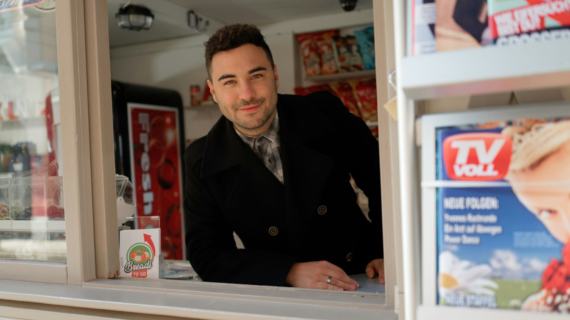 Der Schauspieler Lars Steinhöfel steht lächelnd in der Kulisse der RTL-Fernsehserie „Unter uns“.