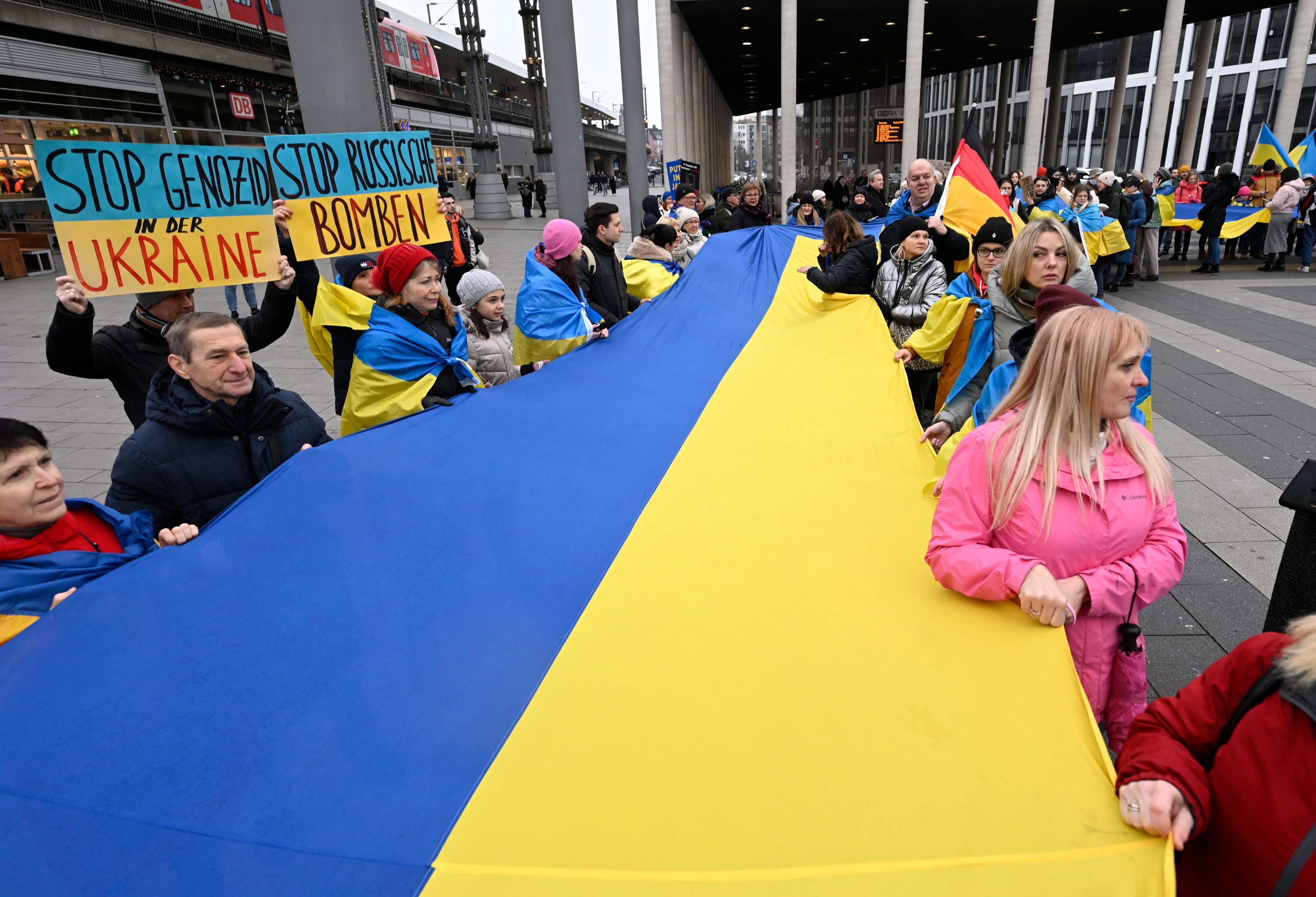 Demonstranten und Demonstrantinnen halten am Kölner Hauptbahnhof eine riesige Fahne der Ukraine in den Händen.