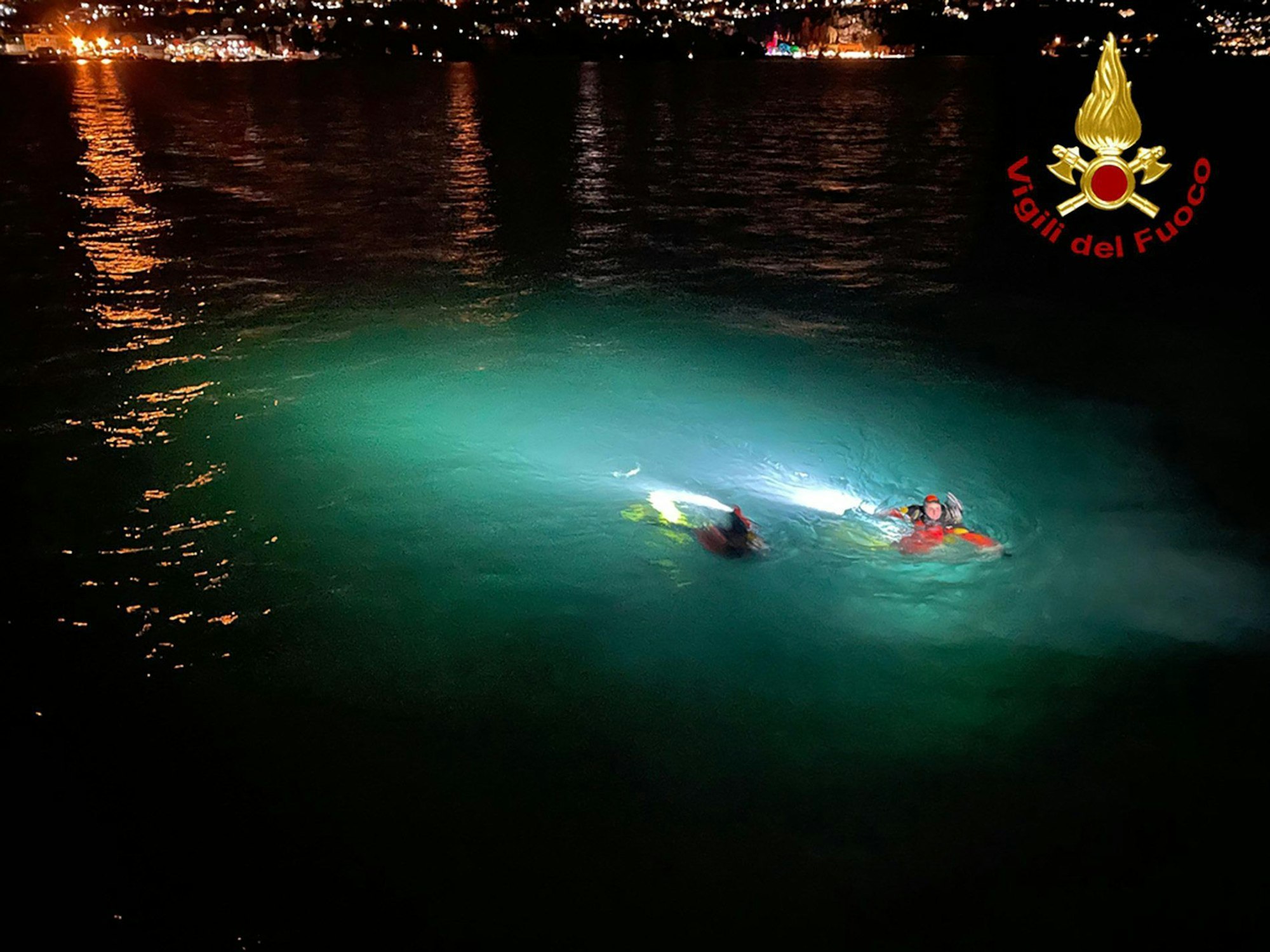 Rettungskräfte schwimmen im Comer See, in den zwei Menschen mit ihrem Auto gestürzt sind.