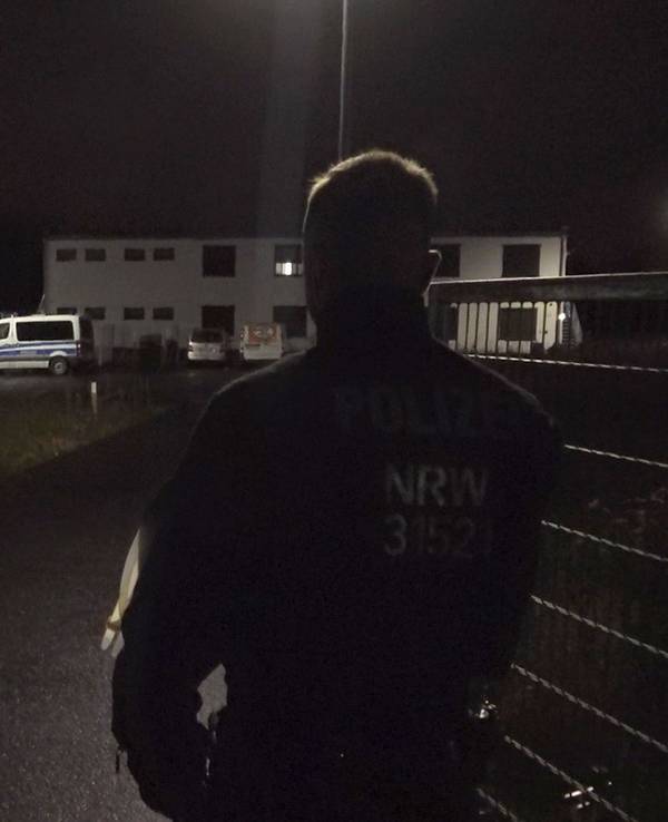 Ein Polizist steht am Tor zu einer Flüchtlingsunterkunft in Sankt Augustin. Eine vermisste Jugendliche ist am Sonntagabend tot in der Unterkunft gefunden worden.