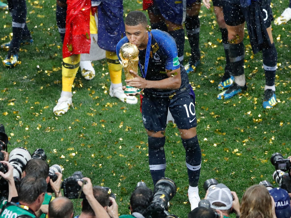 Kylian Mbappé küsst 2018 vor Fotografen den WM-Pokal.
