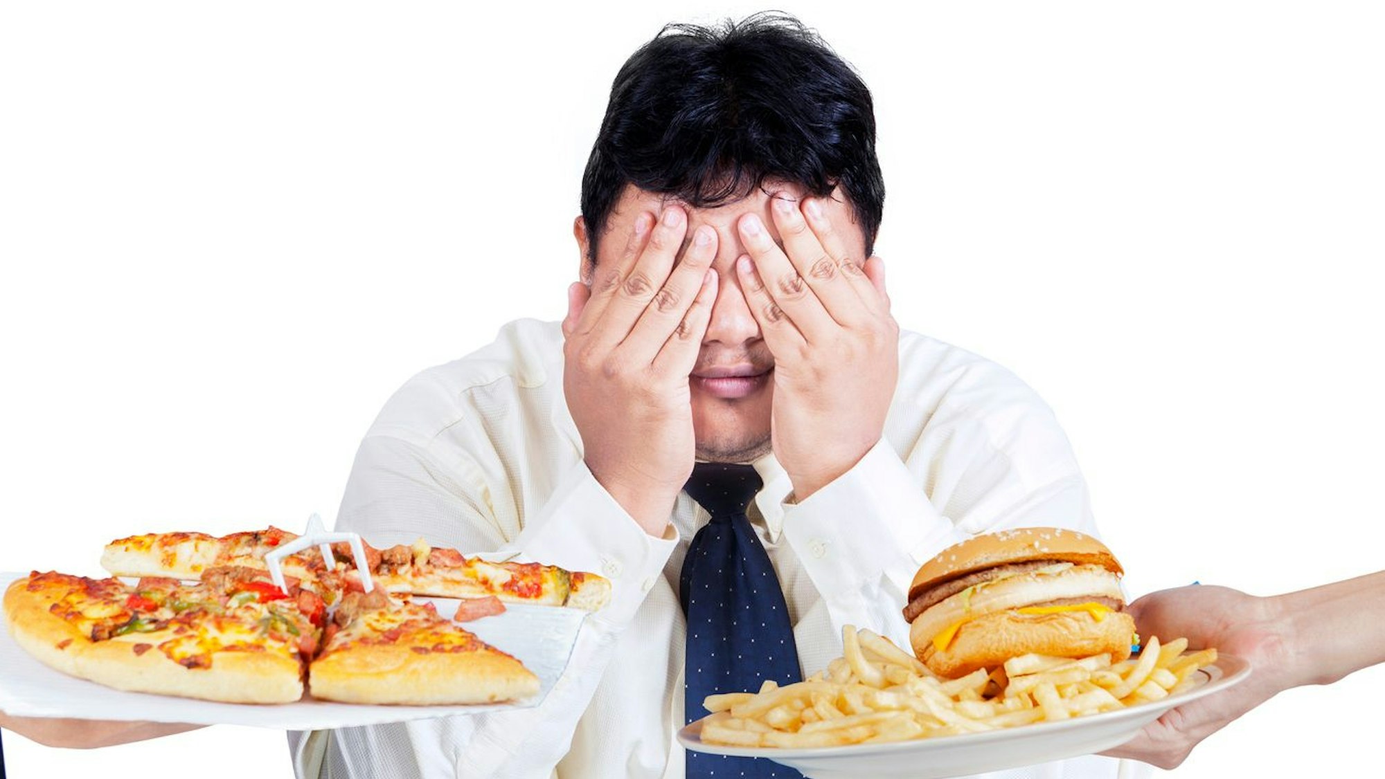 Ein junger Mann hält sich die Augen zu. Er kann sich zwischen Pizza und Burger mit Pommes nicht entscheiden.