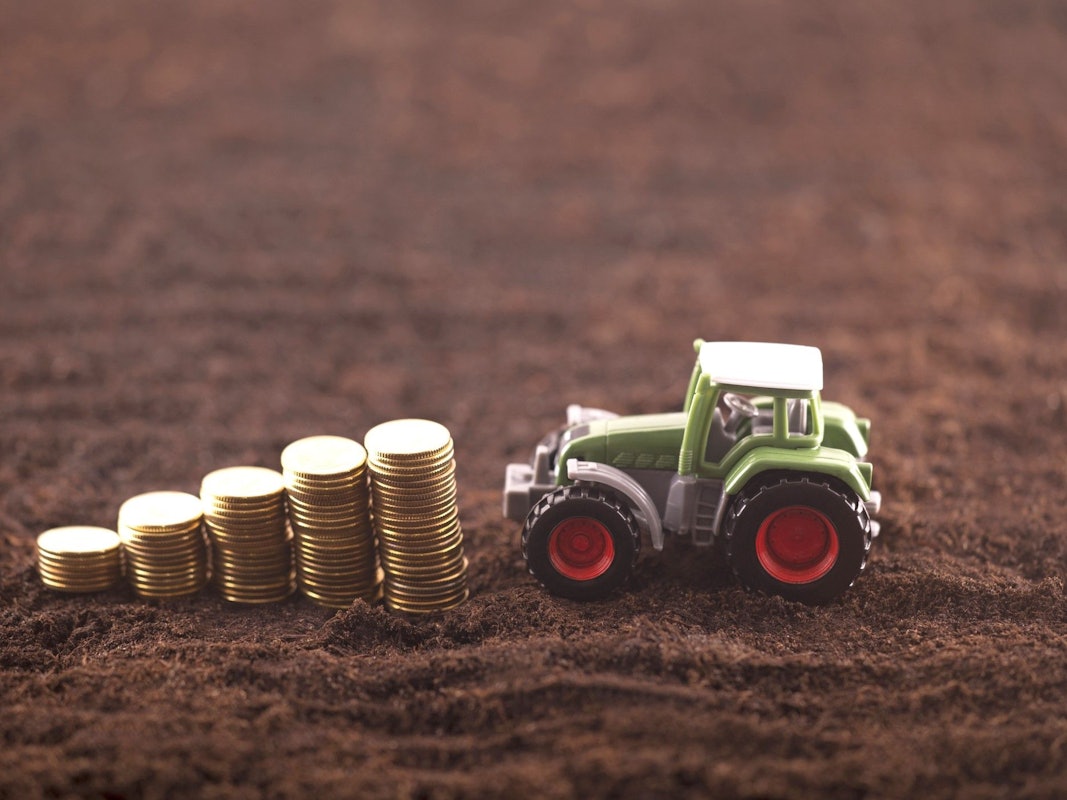 Ein Spielzeugtraktor fährt auf einen Stapel mit Münzen zu.