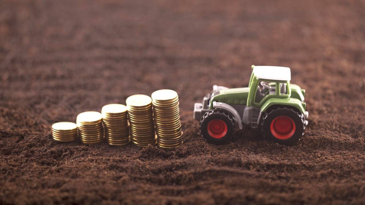 Ein Spielzeugtraktor fährt auf einen Stapel mit Münzen zu.