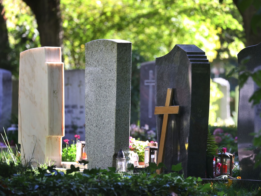 Grabsteine stehen auf einem Friedhof.