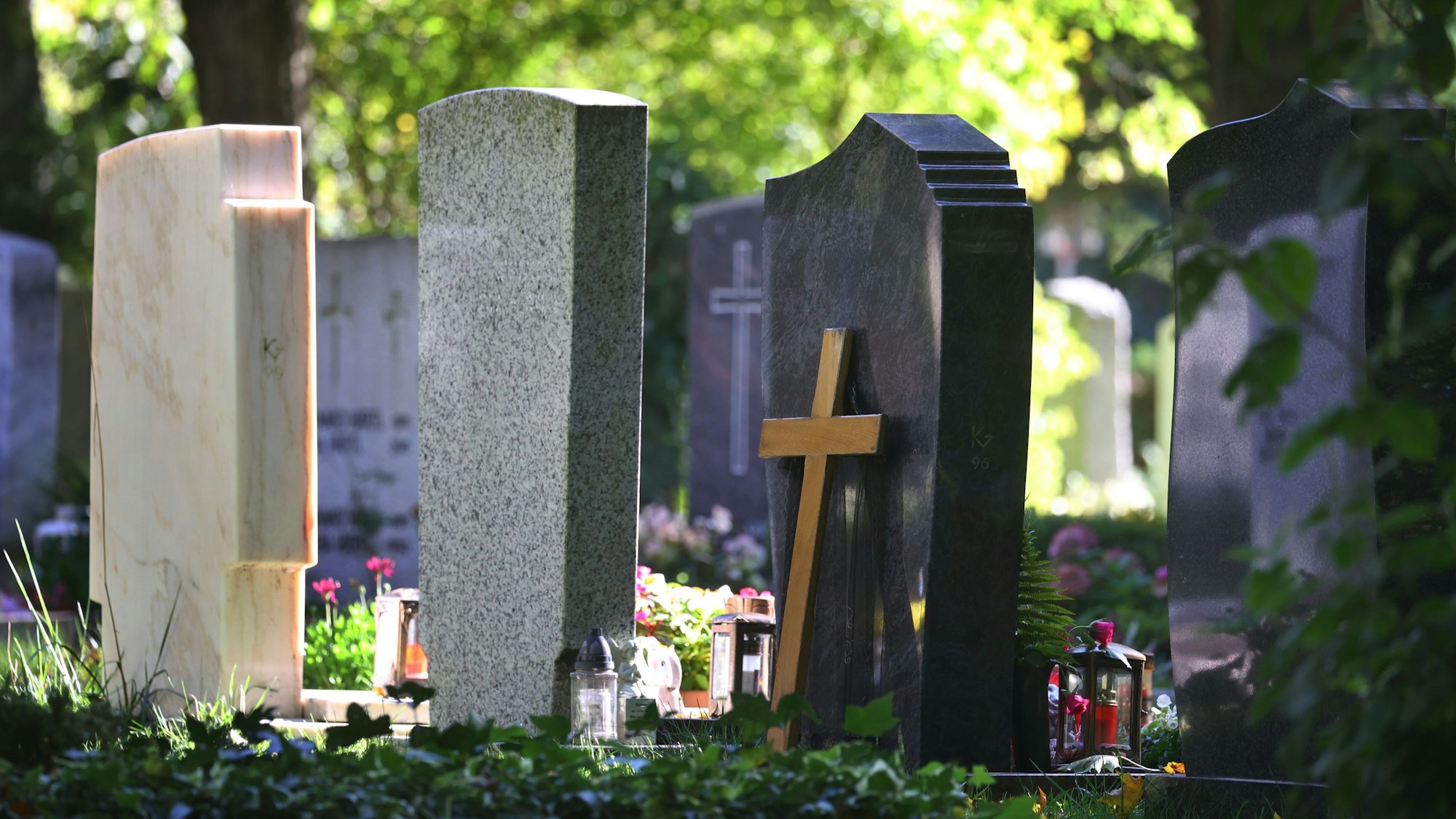 Grabsteine stehen auf einem Friedhof.