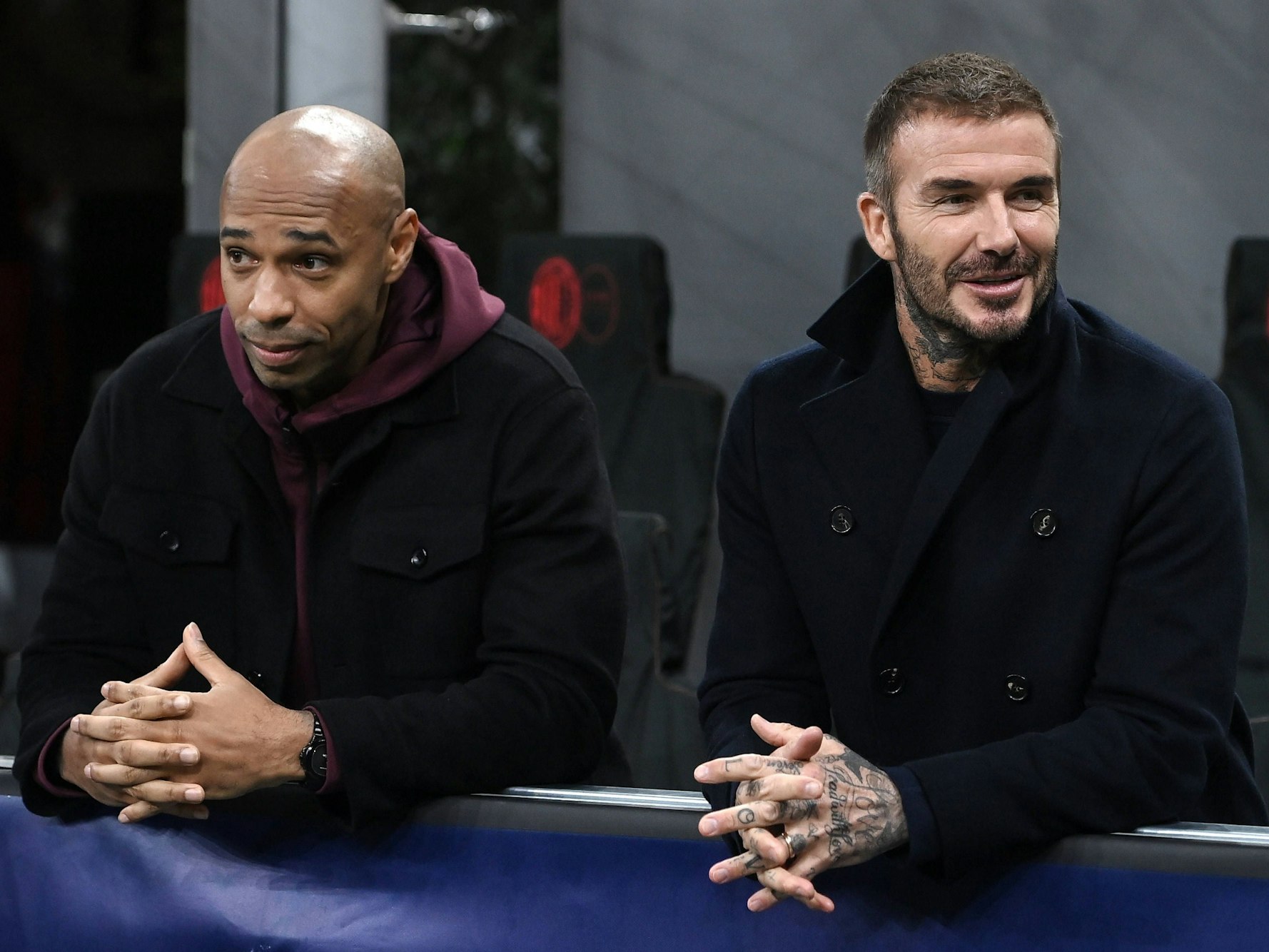 Thierry Henry (l.) und David Beckham stehen am Spielfeldrand, hinter einer Bande.