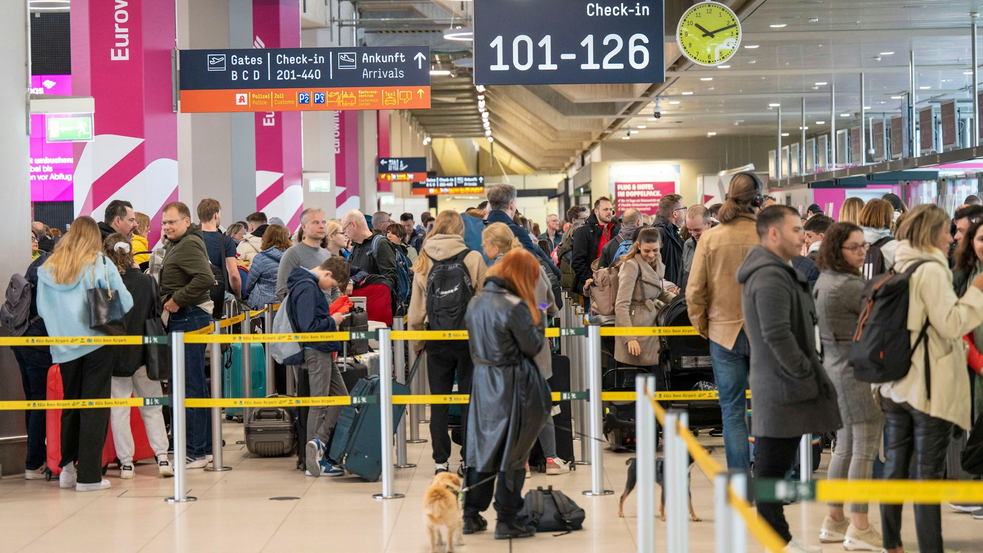 Menschen warten am Check-in am Flughafen Köln/Bonn in einer langen Schlange.