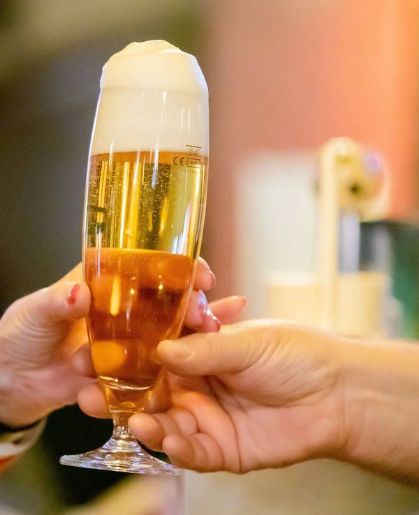 Ein Kneipenwirt reicht in einer Berliner Gaststätte einem Gast ein Bier, hier im Februar 2023.