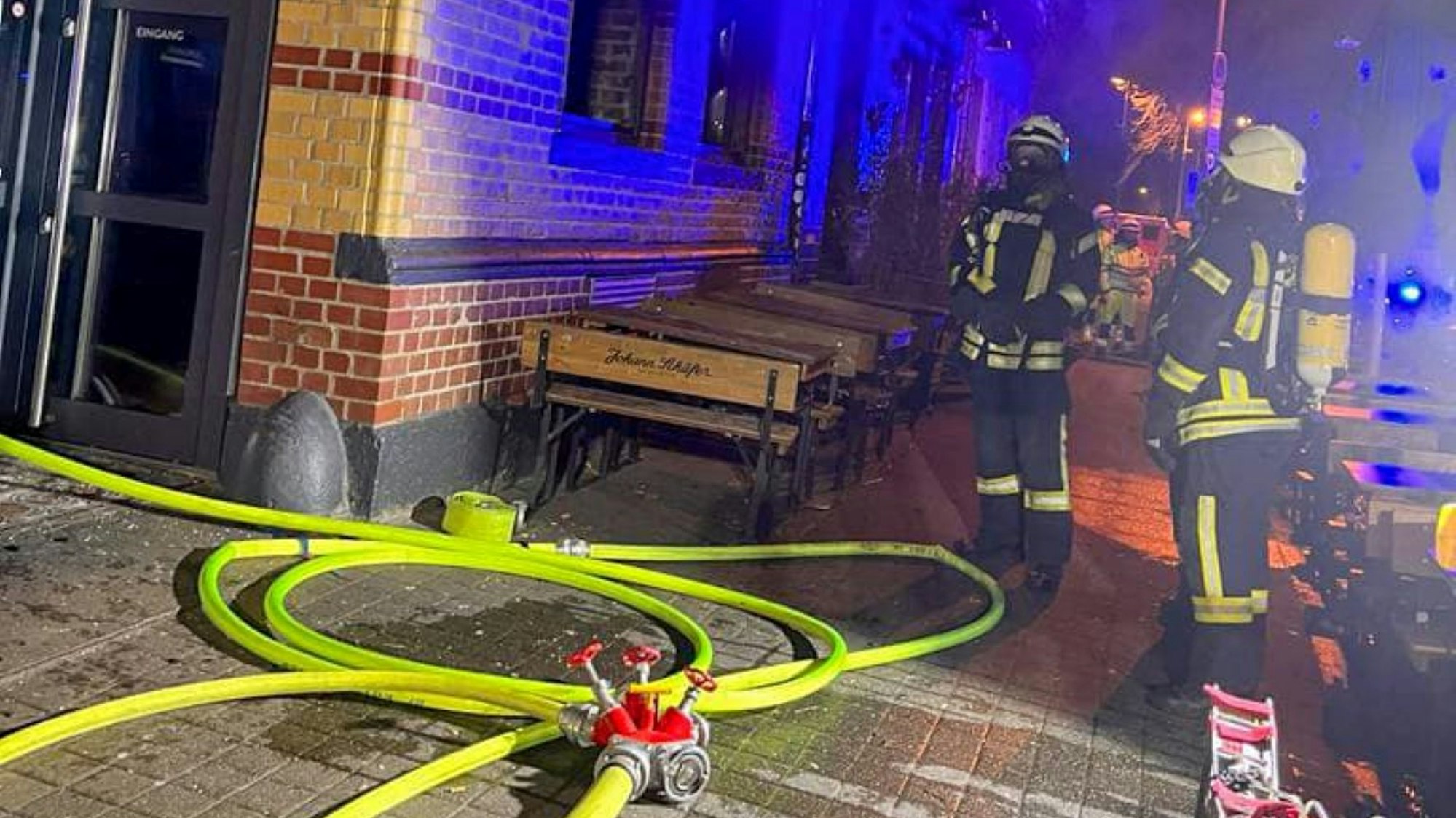 Aus dem Brauhaus dringt Rauch nach draußen, vor dem Haus liegen Löschschläuche, stehen zwei Feuerwehrleute.