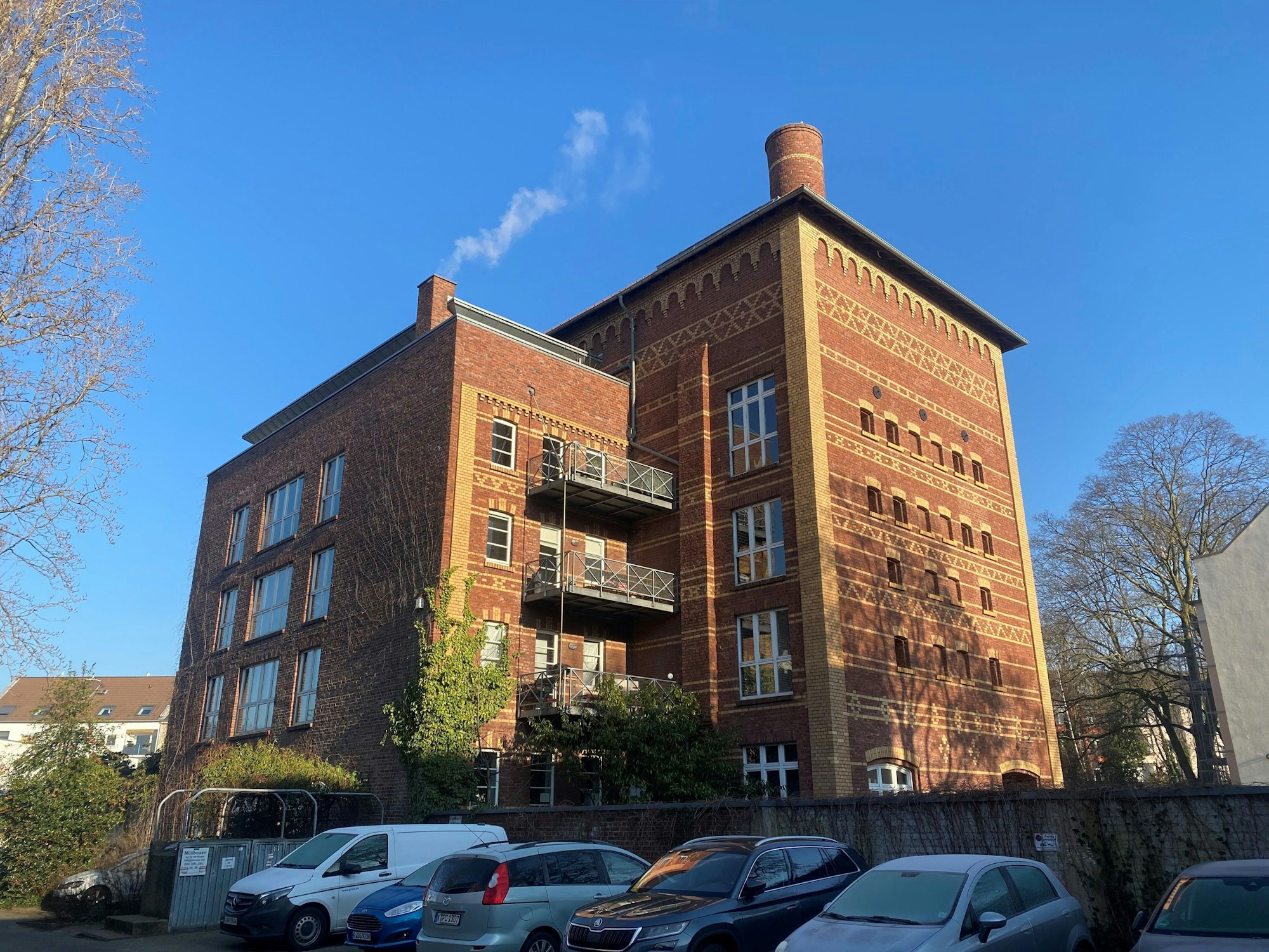 Blick von außen auf ein Denkmal in Köln, davor stehen Autos.