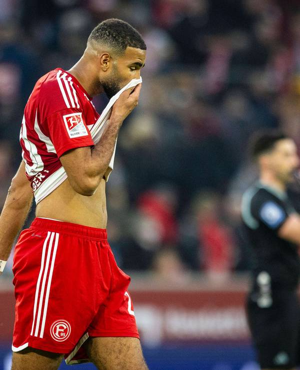 Fortuna Düsseldorfs Abwehrspieler Jamil Siebert läuft beim Spiel gegen Holstein Kiel über den Platz und zieht sich sein Trikot ins Gesicht.