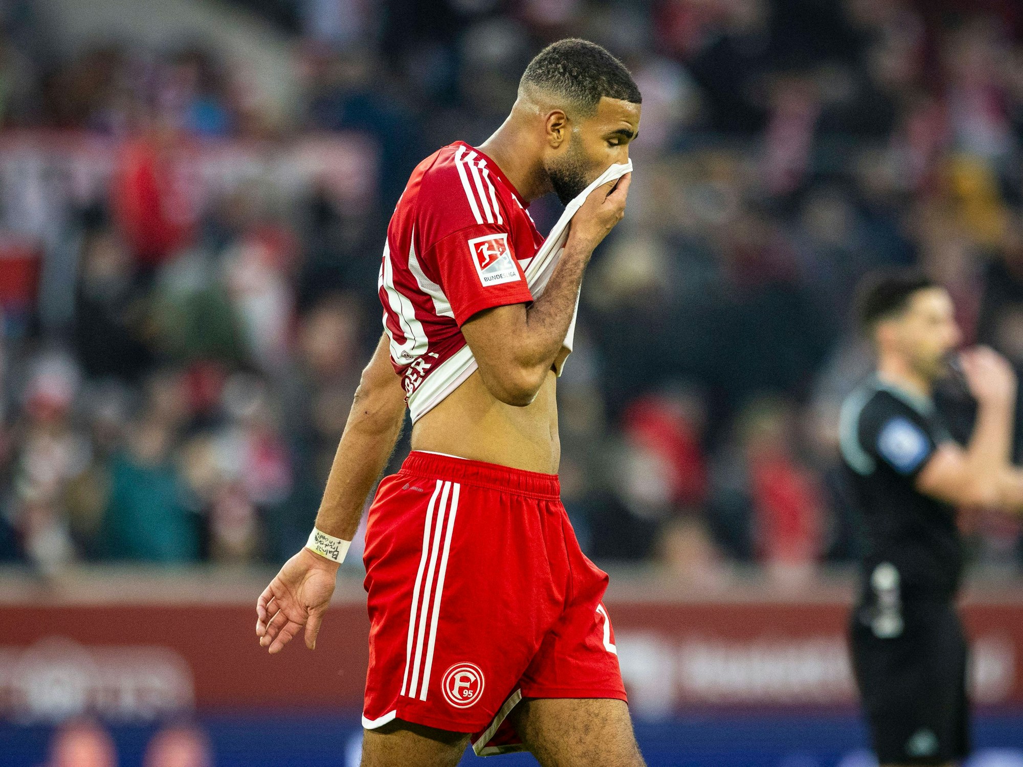 Fortuna Düsseldorfs Abwehrspieler Jamil Siebert läuft beim Spiel gegen Holstein Kiel über den Platz und zieht sich sein Trikot ins Gesicht.