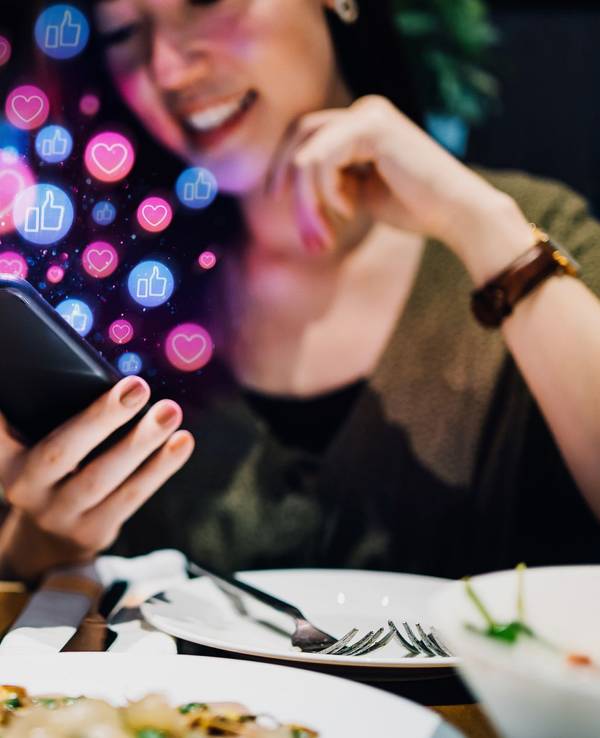Junge Frau schaut glücklich auf ihr Smartphone