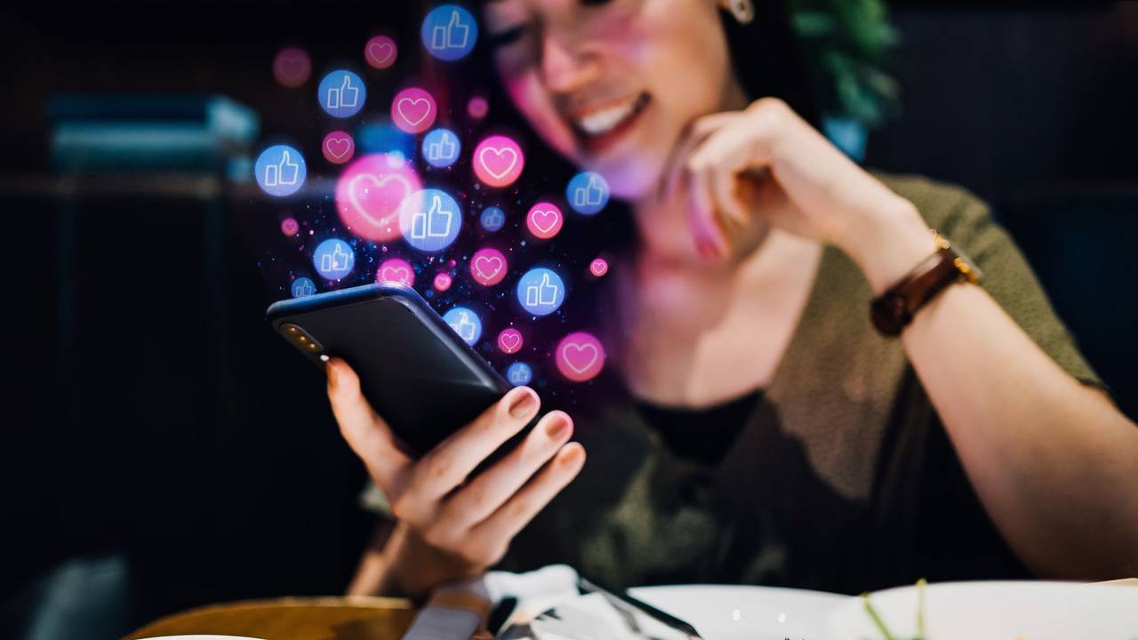 Junge Frau schaut glücklich auf ihr Smartphone