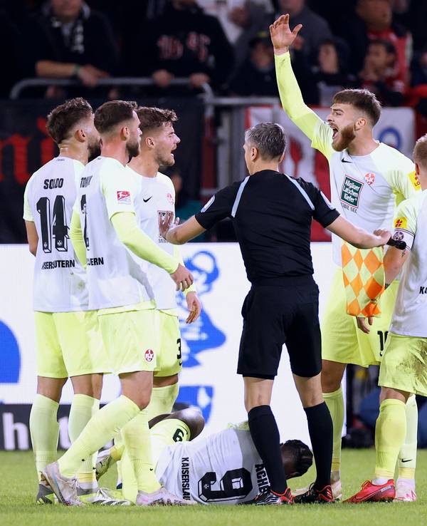 Stürmer Ragnar Ache vom 1. FC Kaiserslautern liegt beim Spiel in Düsseldorf am Boden, seine Teamkollegen und der Schiedsrichter bilden einen Kreis um ihn.