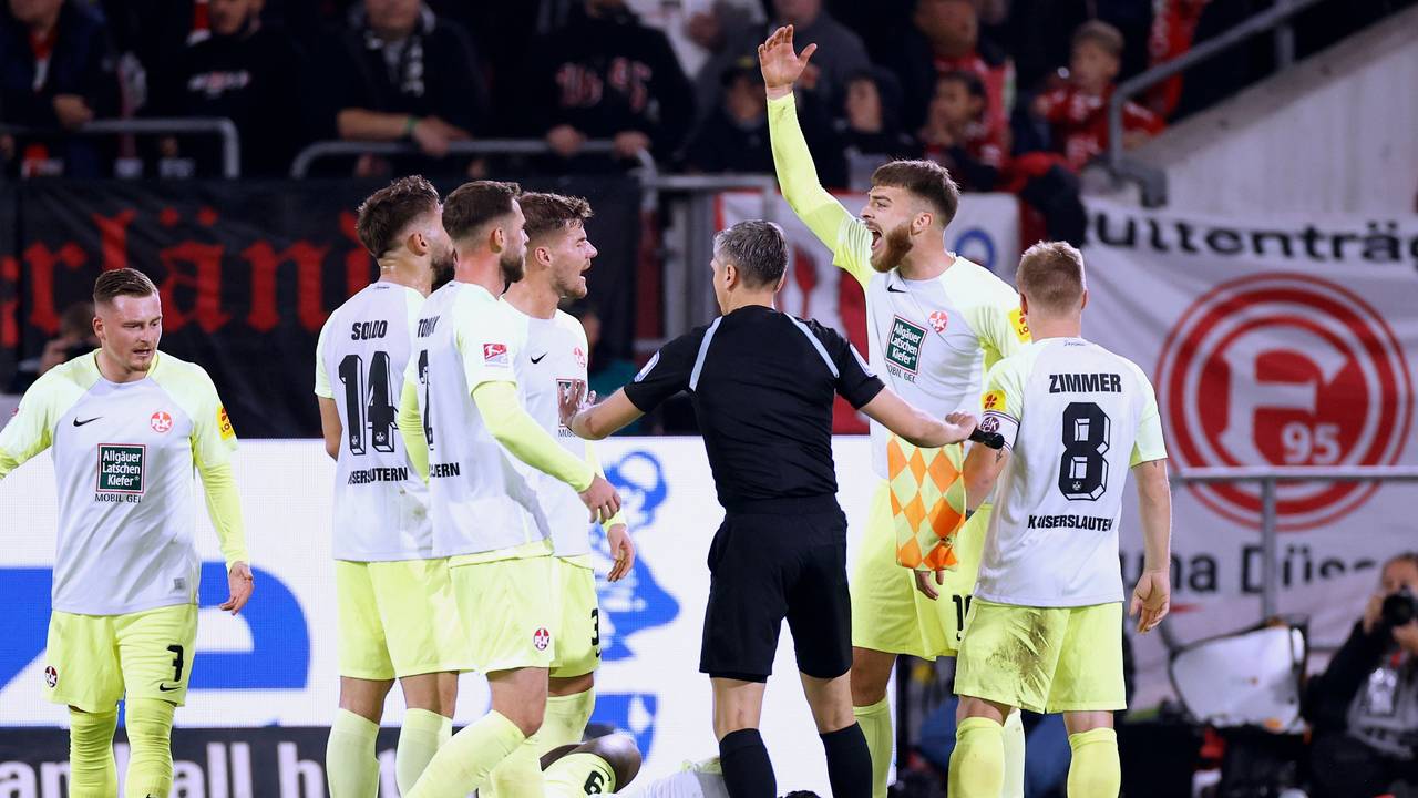 Stürmer Ragnar Ache vom 1. FC Kaiserslautern liegt beim Spiel in Düsseldorf am Boden, seine Teamkollegen und der Schiedsrichter bilden einen Kreis um ihn.