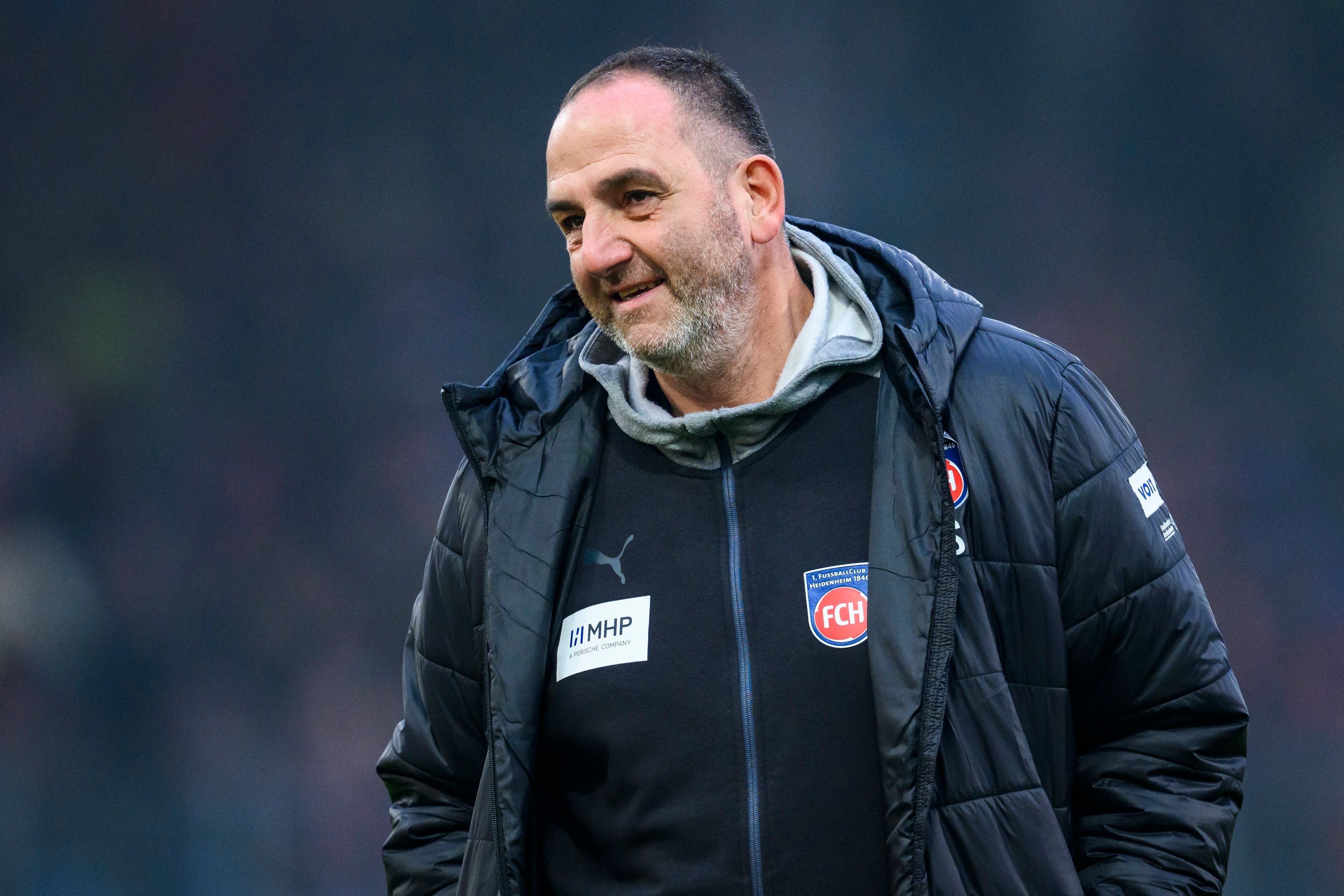 Heidenheims Trainer Frank Schmidt lächelt im Stadion.