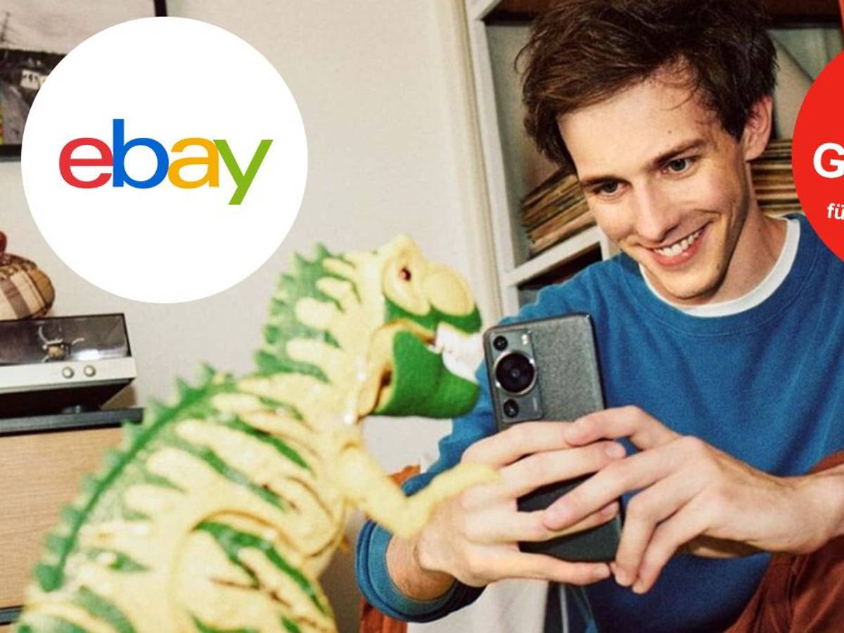 Junger Mann schießt mit dem Smartphone ein Bild von einem Spielzeug-Dinosaurier. Ebay Logo auf Bild.