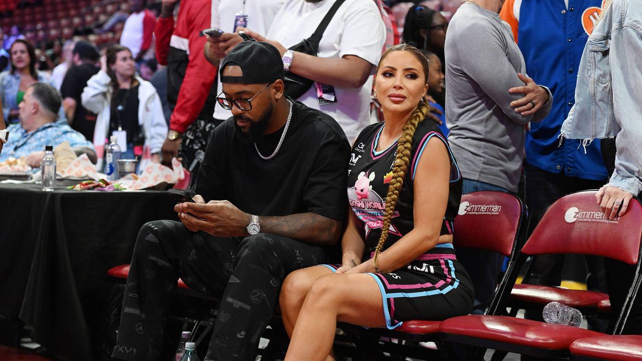 Larsa Pippen und Marcus Jordan sitzen am Rand eines Basketball-Spielfelds.